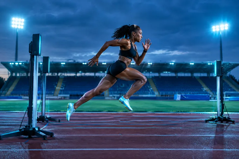 Sprinter trains past a timing gate on a stadium track; editorial illustration