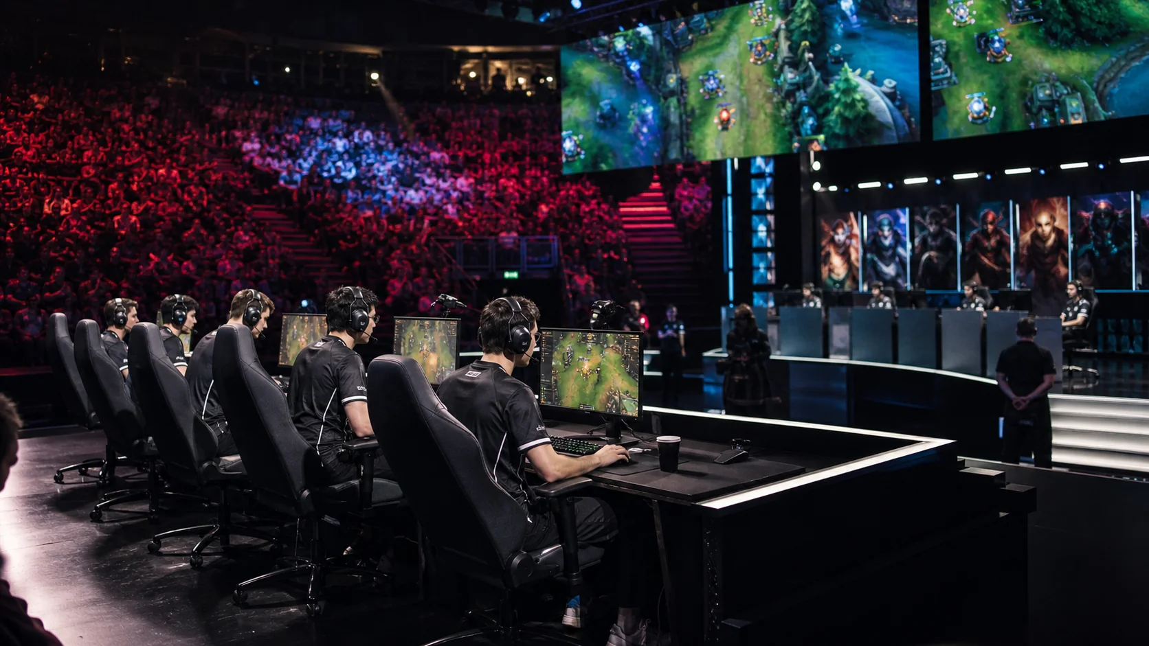 Two esports teams competing at gaming PCs with headsets before a live tournament audience